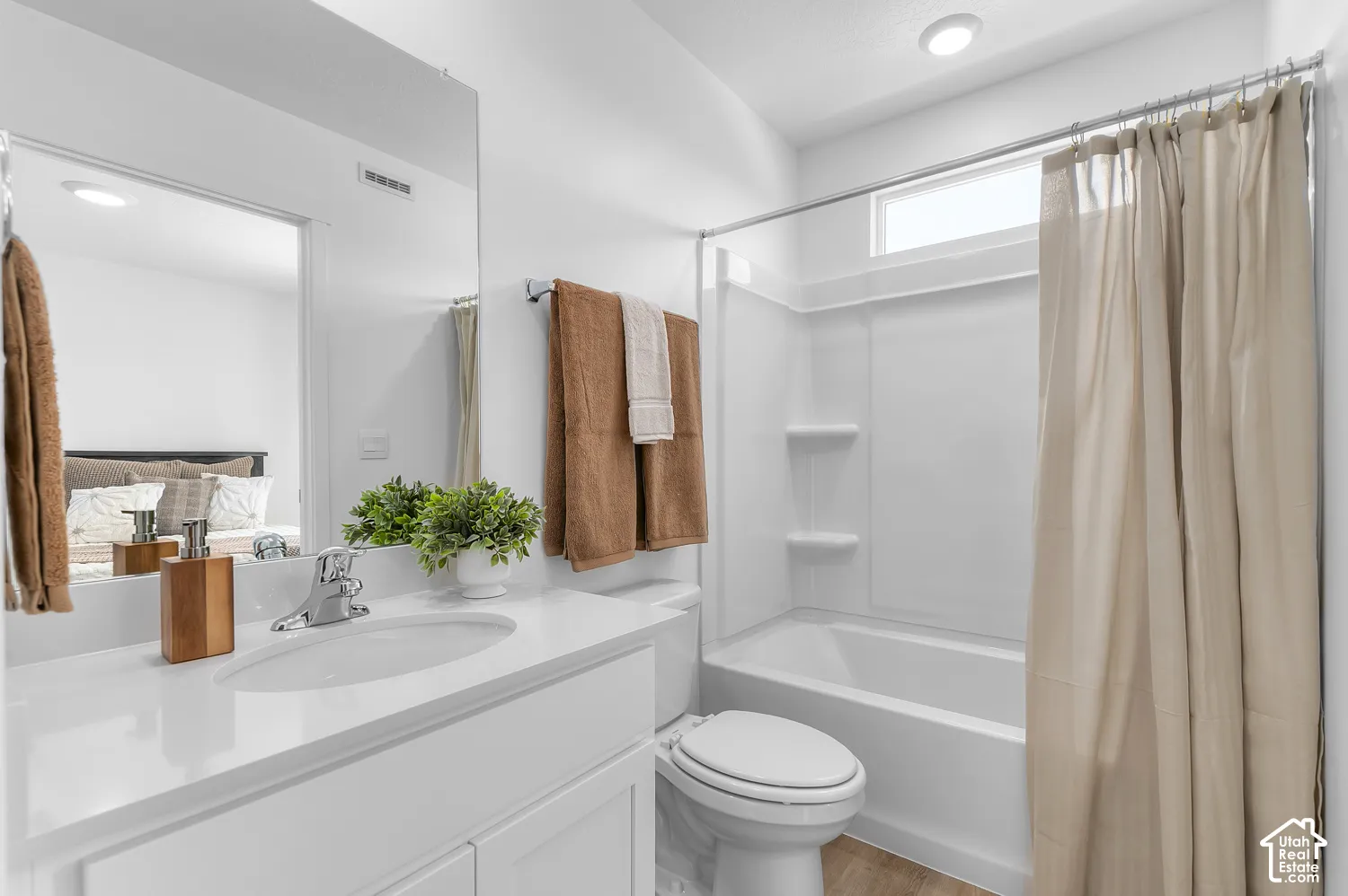 White vanity with integrated sink, chrome faucet, and expansive mirror