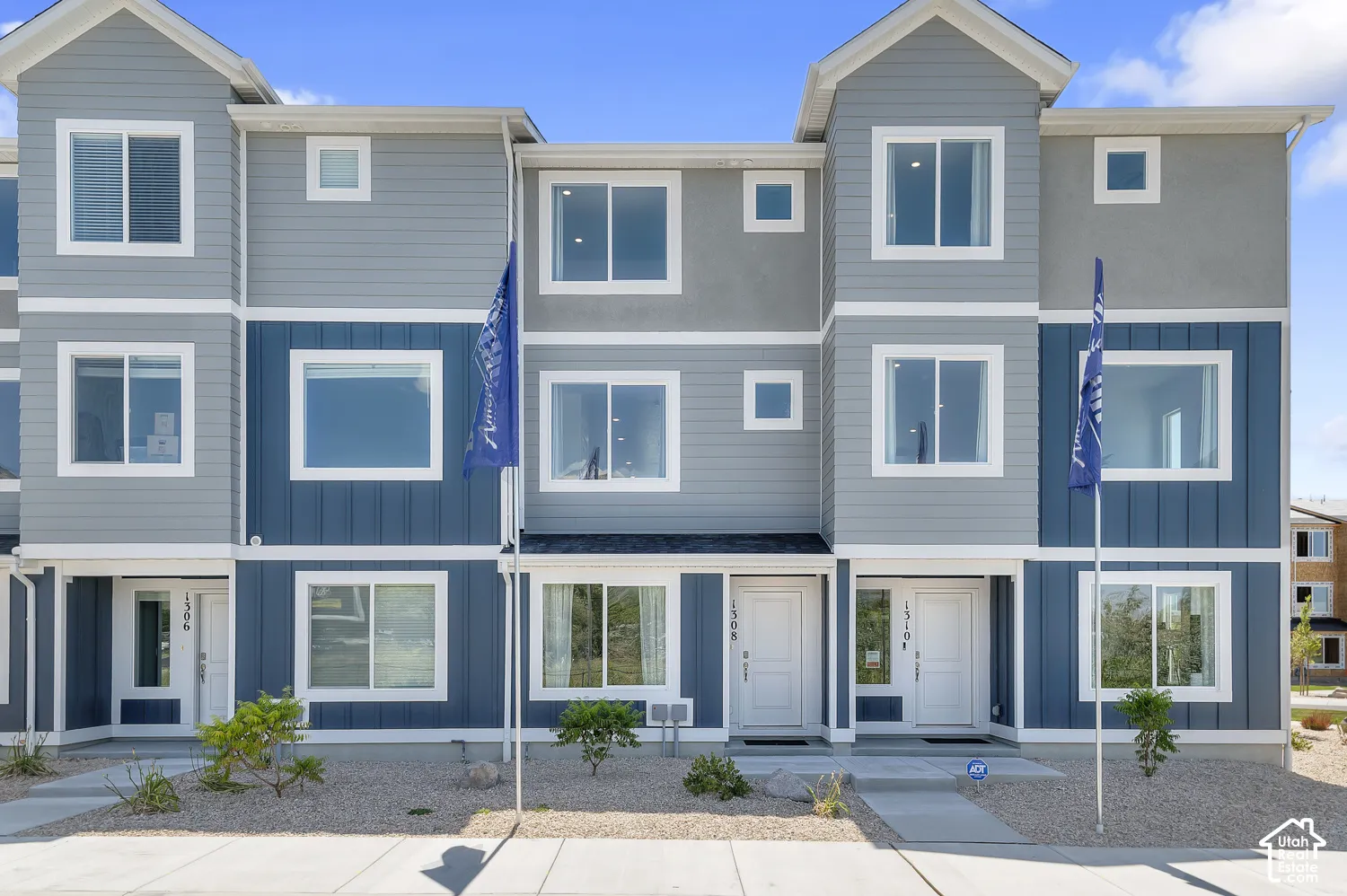 Contemporary multi-story exterior featuring two-tone siding, multiple windows, and a paved walkway