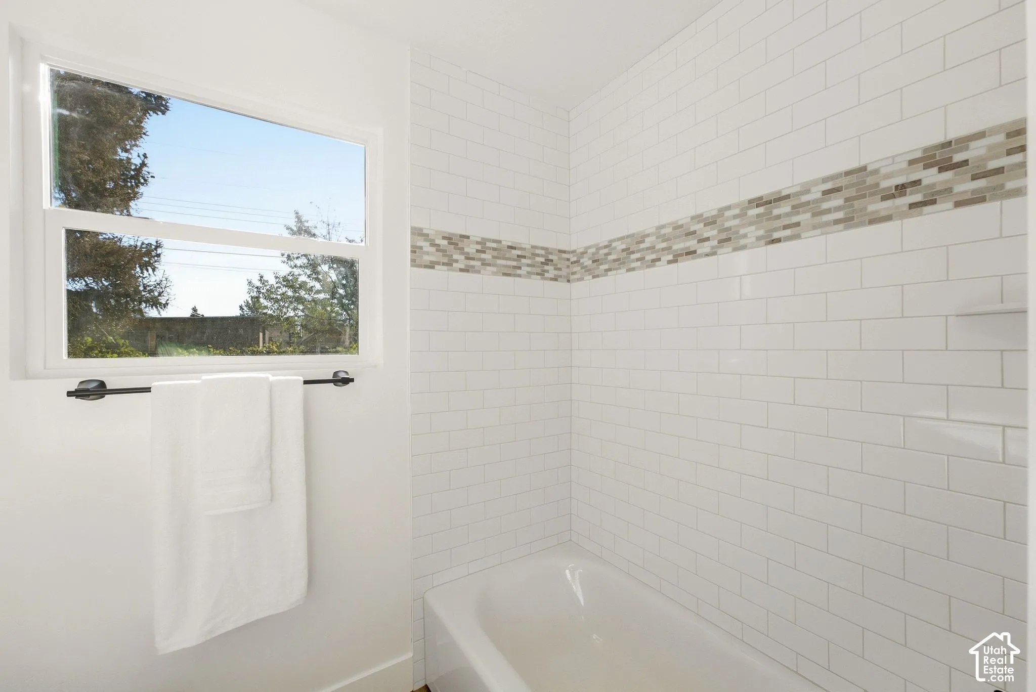 Subway tile surround with a mosaic accent band, integrated shelving, and a built-in tub