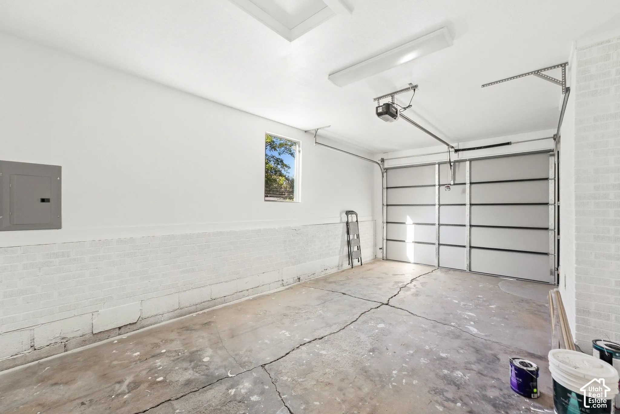 Attached garage featuring a panel garage door, overhead lighting, and an electrical panel