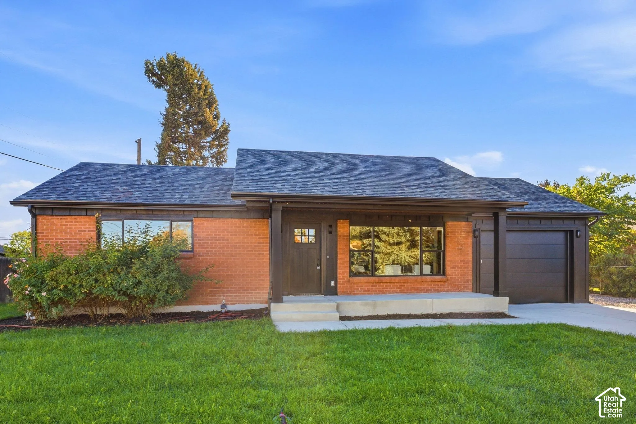 Brick exterior with dark trim accents, asphalt shingle roof, and an attached garage with a modern door