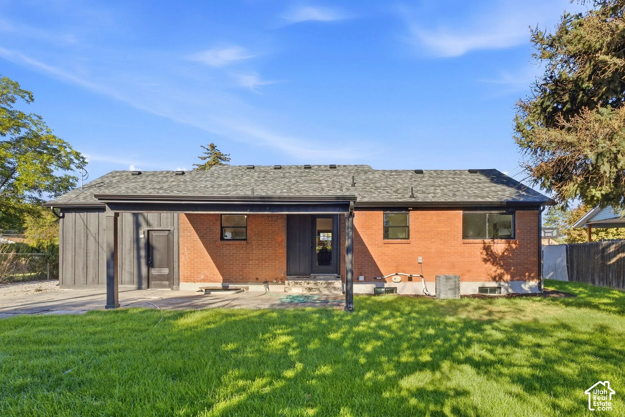 Expansive green lawn with a brick exterior, a covered patio, and a shingle roof