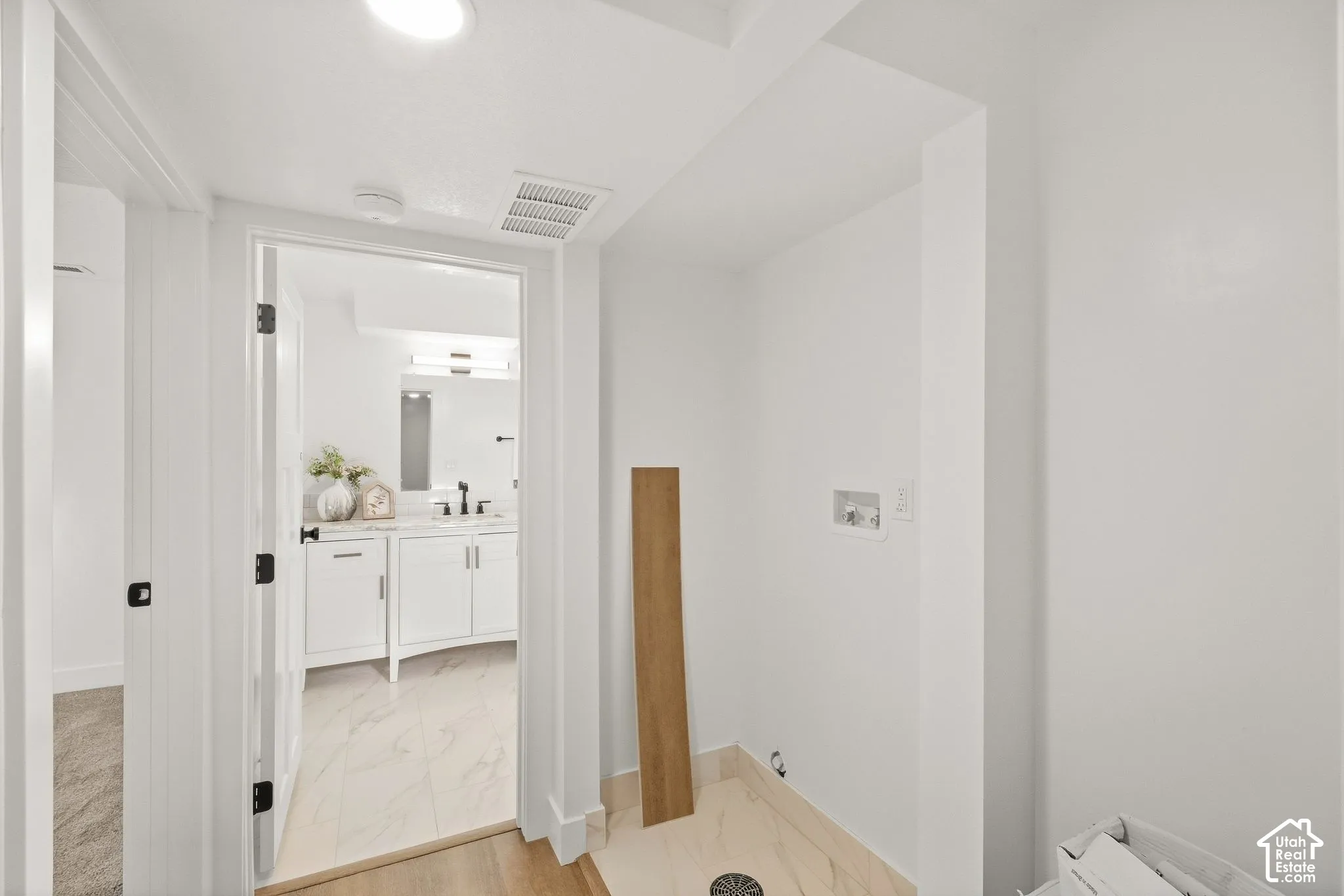 Recessed ceiling lighting illuminates a hallway with stone-finish tile flooring