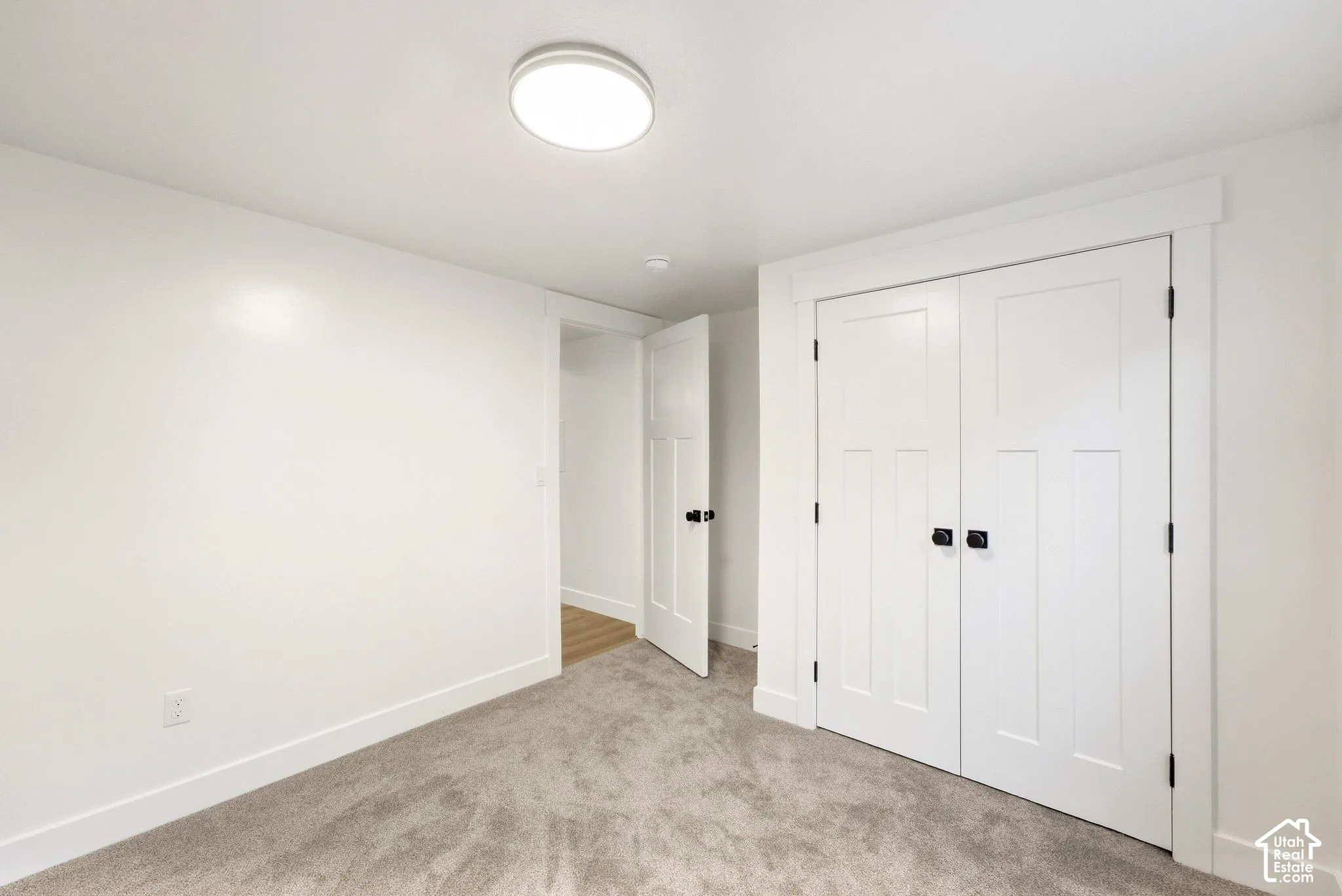 Recessed lighting, wall-to-wall carpeting, white interior doors with black hardware, and crisp white trim