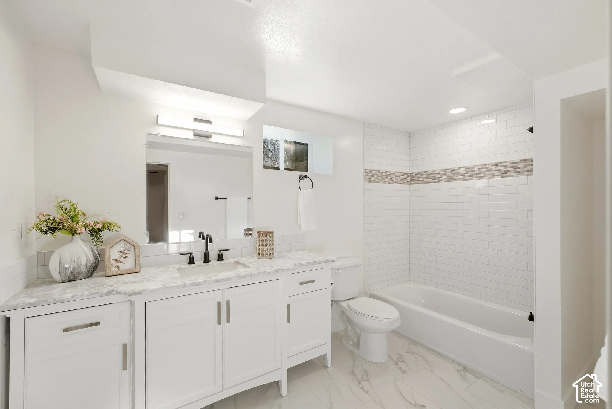 White shaker-style vanity with a light-toned countertop, undermount sink, and matte black faucet
