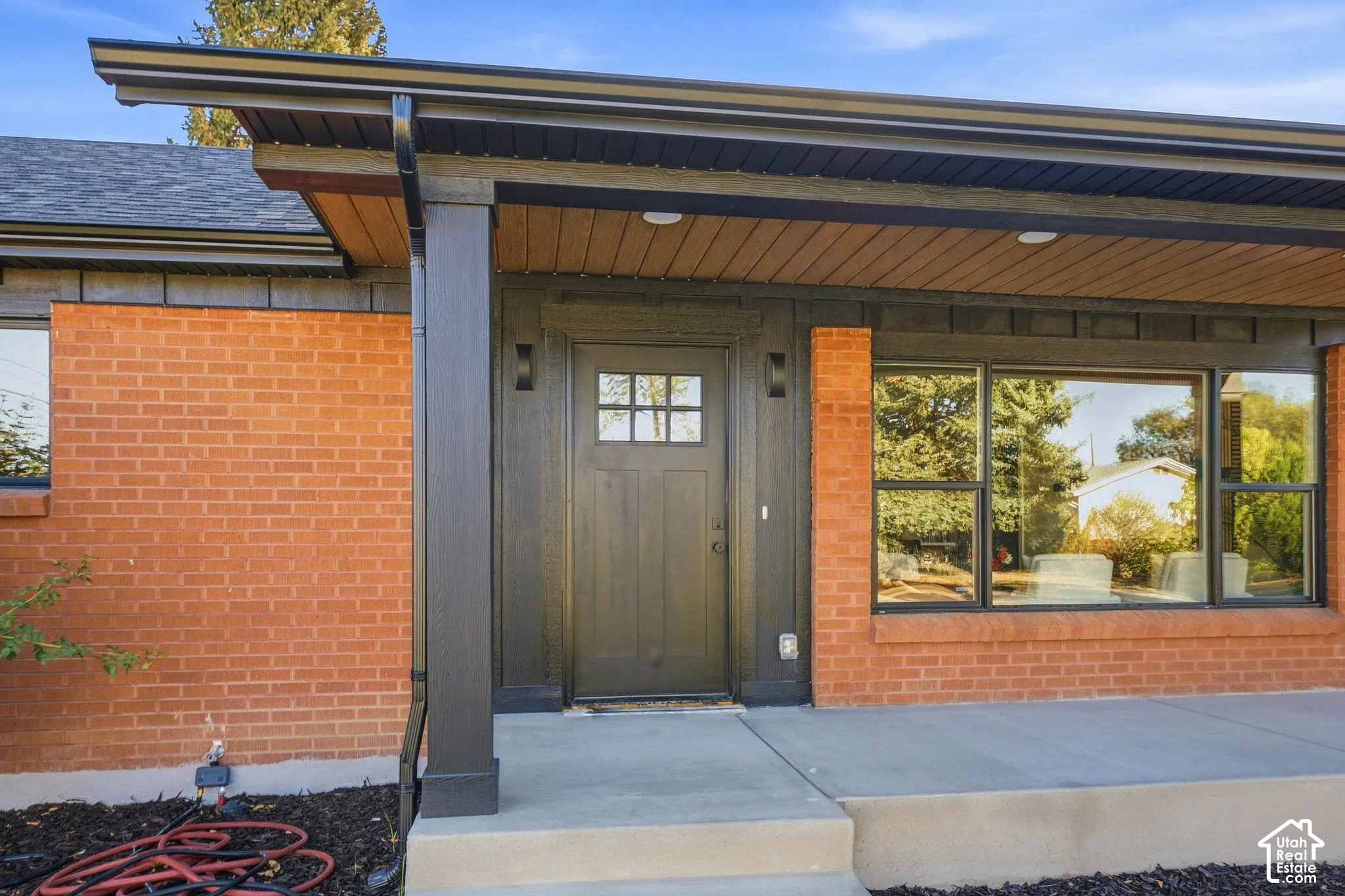 Brick exterior with black trim, concrete walkway, and a dark wood-finish entry door with divided lites