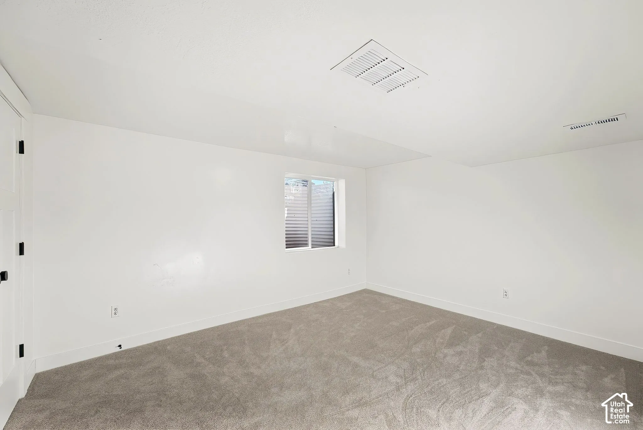 Neutral white walls, light-toned carpeting, and a window with horizontal blinds