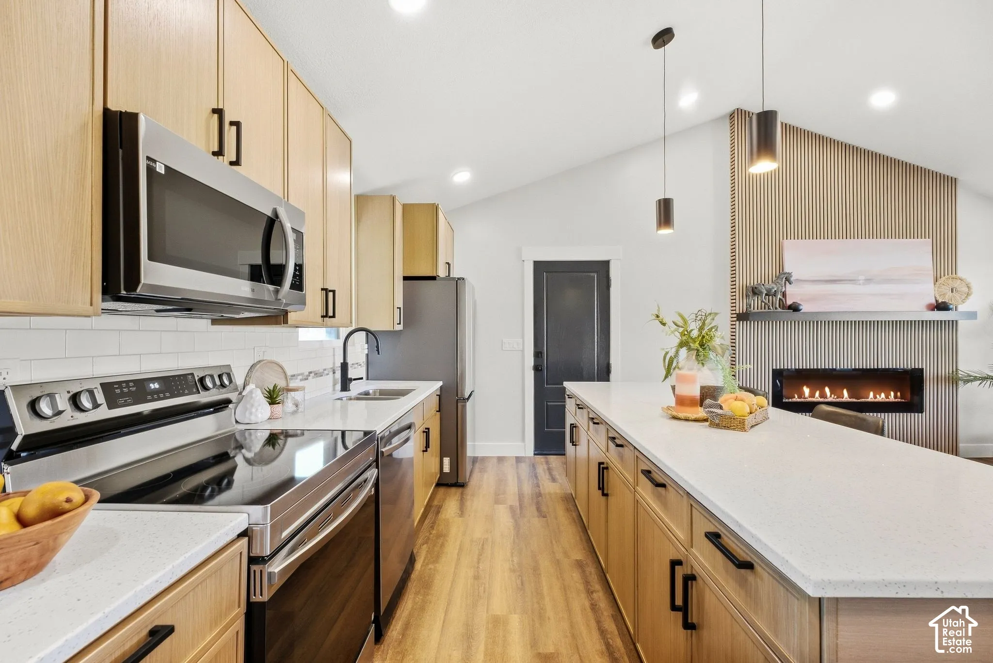 Kitchen featuring wood-finish cabinetry, stainless steel appliances, a white subway tile backsplash, and light-toned countertops