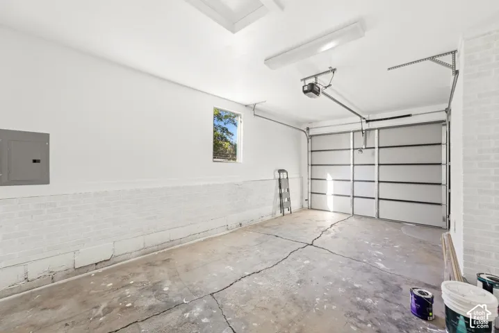 Attached garage featuring a panel garage door, overhead lighting, and an electrical panel