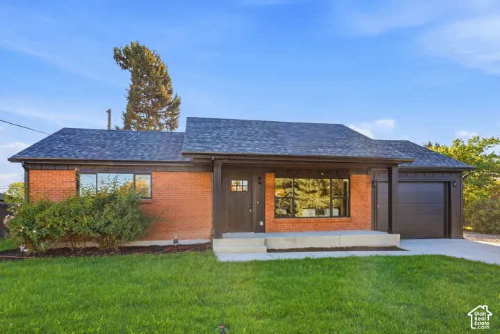 Brick exterior with dark trim accents, asphalt shingle roof, and an attached garage with a modern door