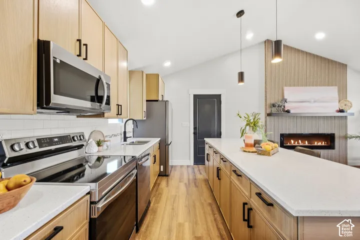 Kitchen featuring wood-finish cabinetry, stainless steel appliances, a white subway tile backsplash, and light-toned countertops