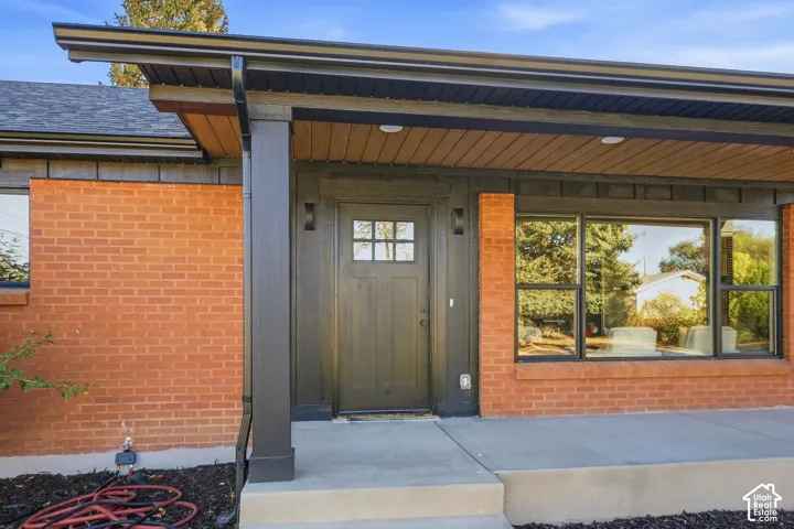 Brick exterior with black trim, concrete walkway, and a dark wood-finish entry door with divided lites