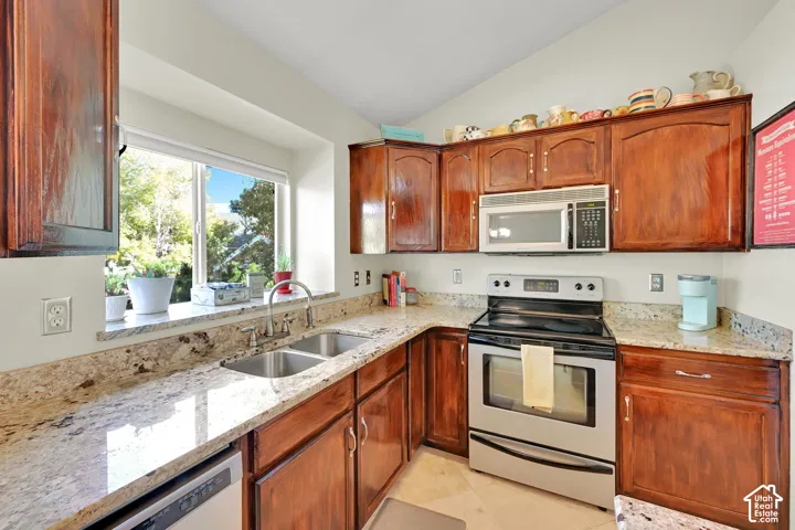 Kitchen featuring wood cabinetry, stainless steel appliances, granite countertops, and a dual basin sink