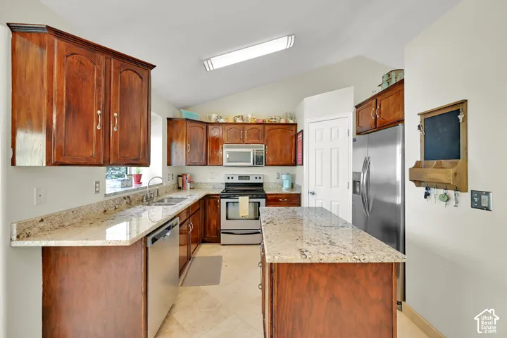 Kitchen featuring wood cabinetry, light-toned countertops, stainless steel appliances, and tile flooring