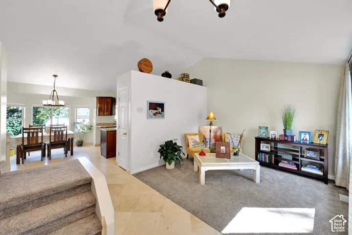 Open-concept living area featuring a vaulted ceiling, staircase with carpeted treads.