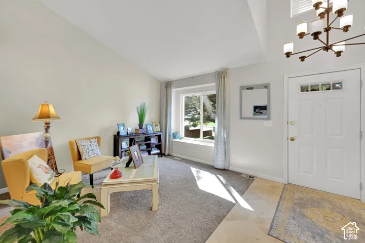 Vaulted ceiling, contemporary chandelier, paneled entry door, bay window, and light-toned tile flooring