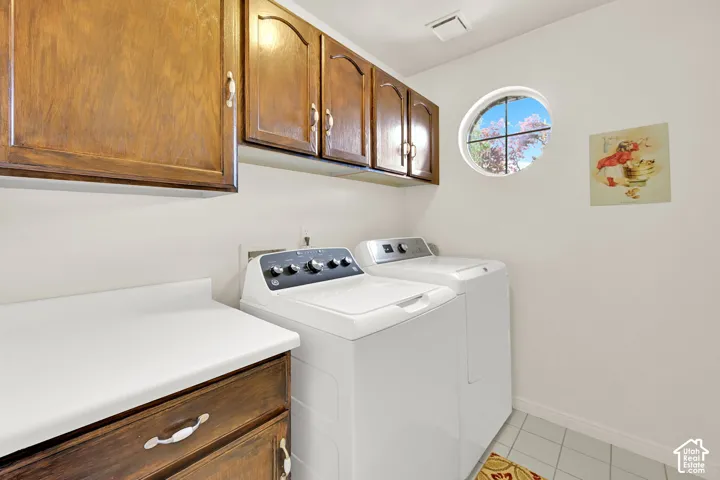 Laundry area featuring wood cabinetry, a round window, white countertop space, and tile flooring