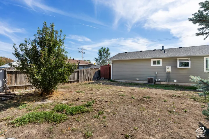 Spacious yard featuring a mature deciduous tree, wood panel fencing, and a gray exterior with white trim
