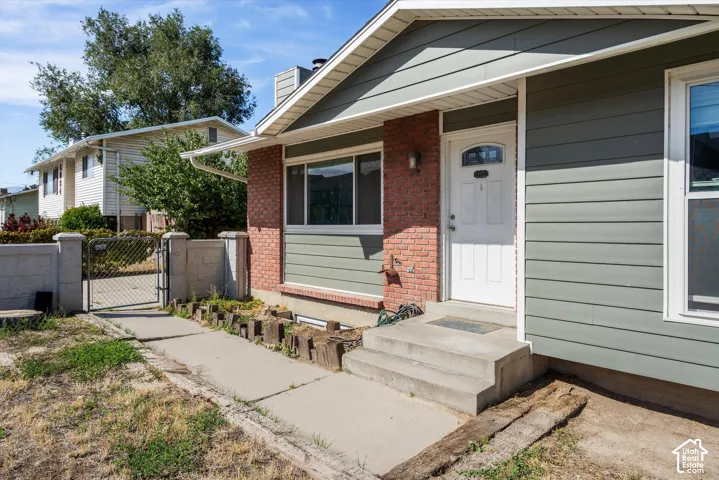 Entry featuring a white paneled door with an overhead transom window, brick facade, and horizontal siding