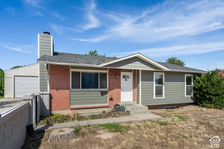Brick and siding exterior with a covered entry, attached garage, and a concrete walkway