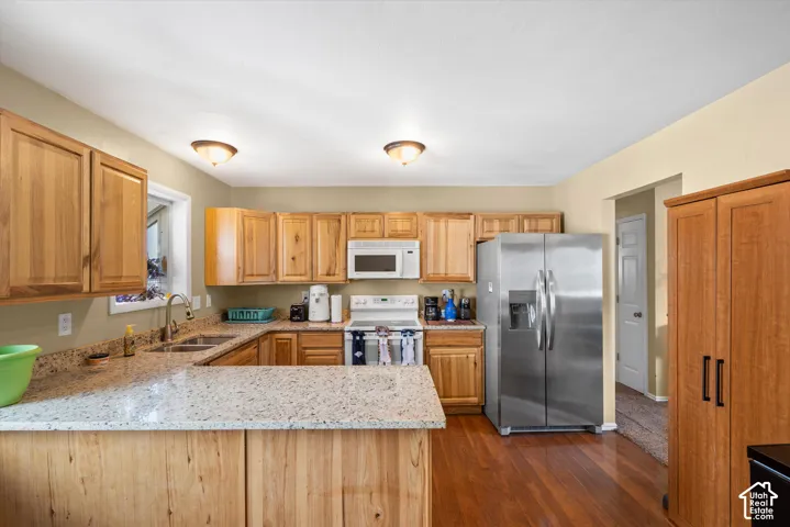 Wood-finish flooring, light wood cabinetry, stone-finish countertops, stainless steel appliances, and a built-in pantry cabinet
