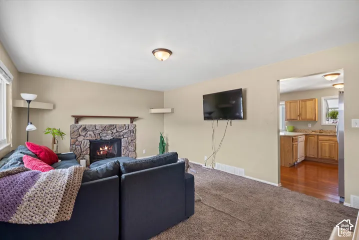 Stone-faced fireplace with a wood mantle, vaulted ceiling, and recessed wall shelving