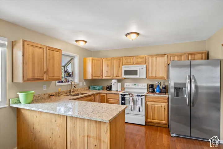 U-shaped kitchen featuring wood cabinetry, granite-finish countertops, and wood-finish flooring