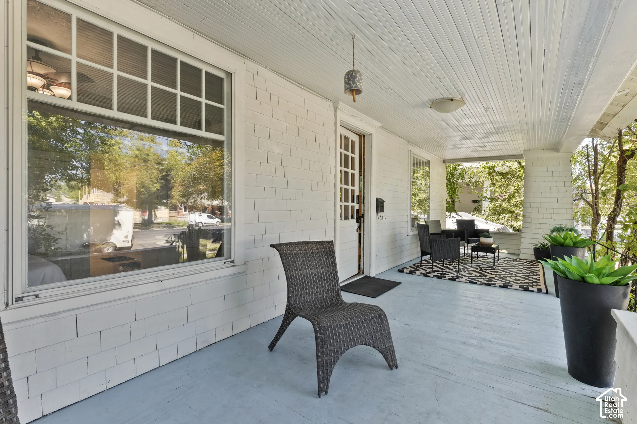 Expansive covered porch featuring a painted wood floor, bead-board ceiling, and white shake siding.