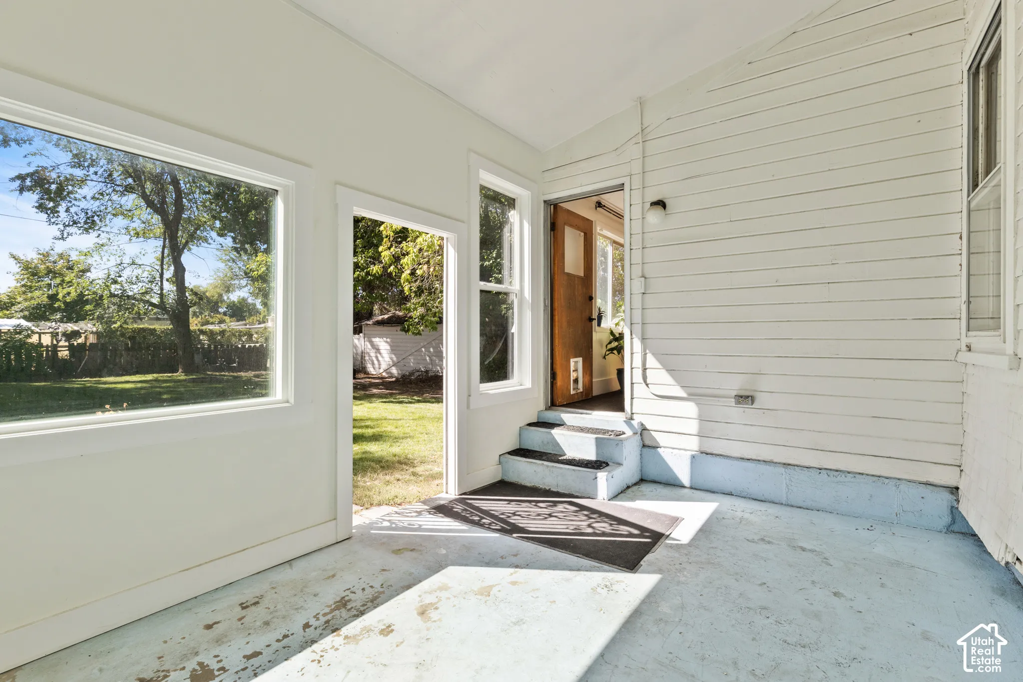 Enclosed back porch & sunroom with large windows & views of backyard