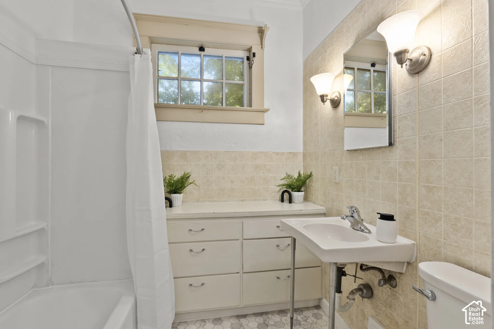 Built-in vanity with drawer storage, tiled walls, hexagon floor tiling, and tub/shower combo