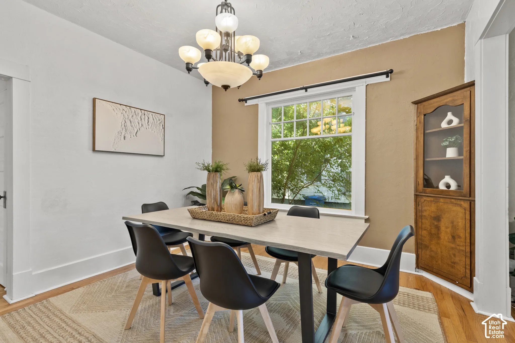 Spacious dining room with built-in corner cabinet, large window, and chandelier
