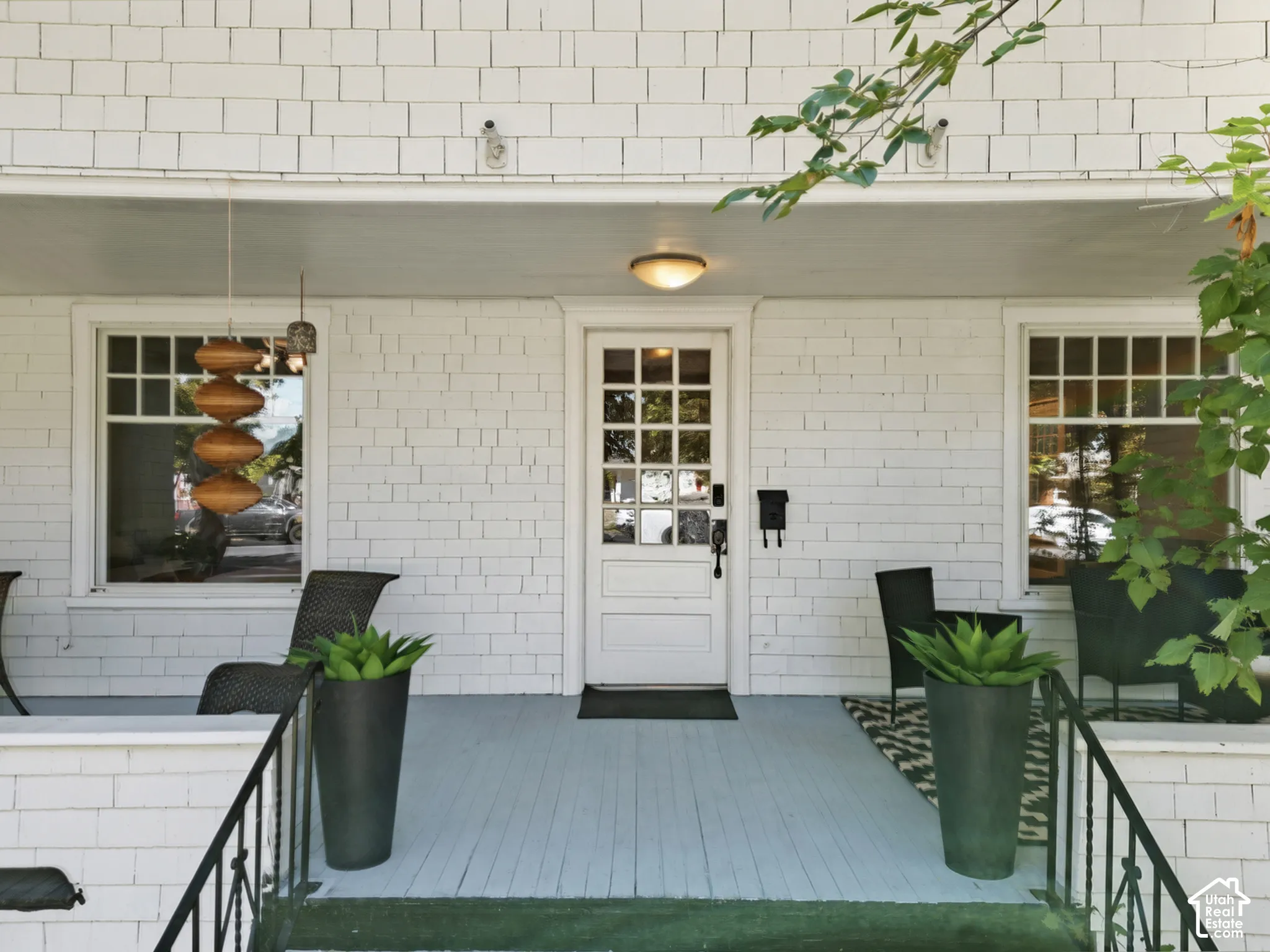 Spacious covered front porch featuring a white wood shake exterior & large windows