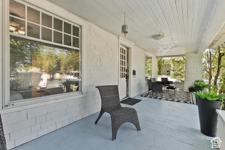 Expansive covered porch featuring a painted wood floor, bead-board ceiling, and white shake siding.