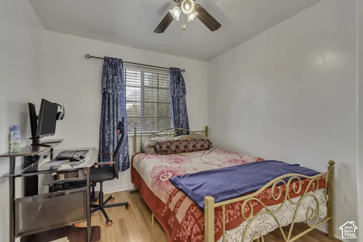 Recessed window with blinds, wood-finish flooring, and a ceiling fan with integrated lighting
