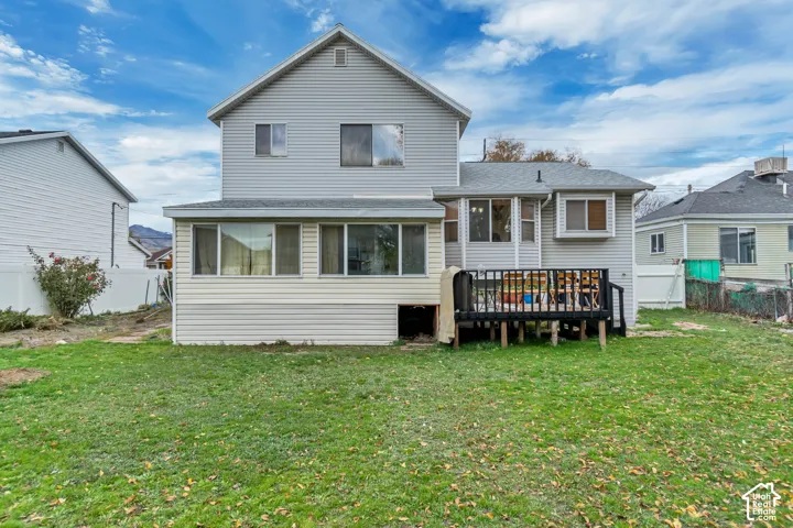 Vinyl siding exterior with a multi-level structure, ground-level sunroom, and an elevated wood deck