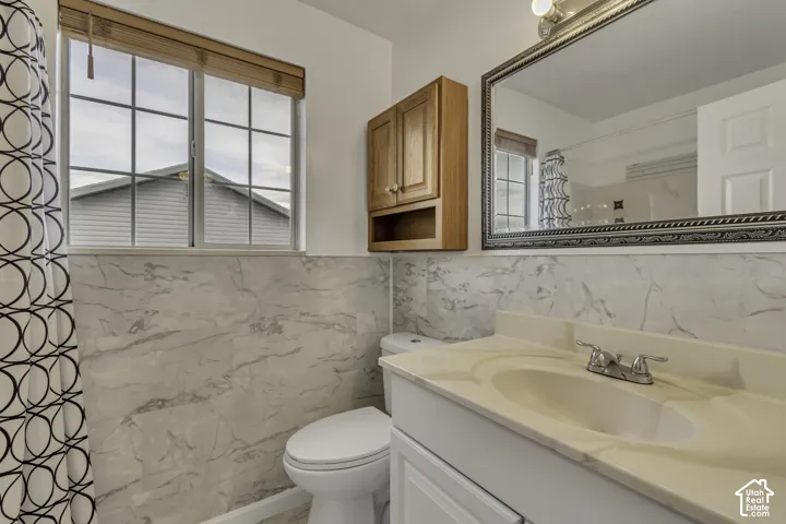 Vanity with integrated sink and chrome faucet, large framed mirror, and wood-finish wall-mounted cabinetry
