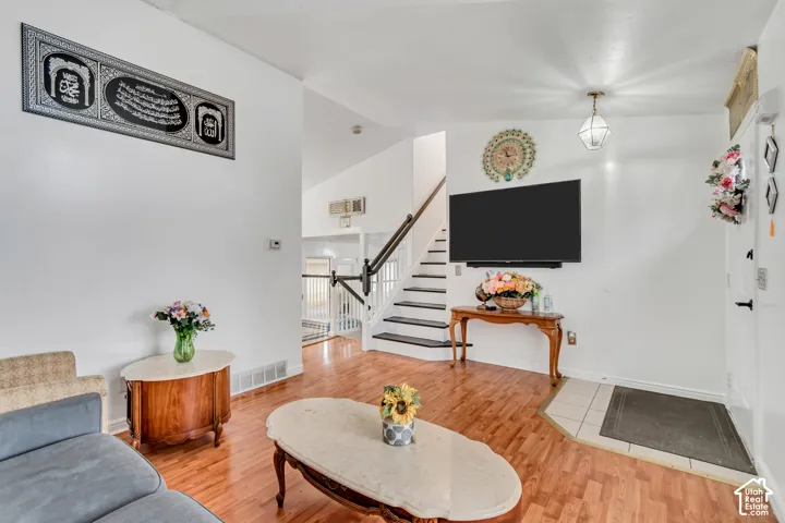 Wood-finish flooring throughout, white painted walls, and a staircase with a dark handrail