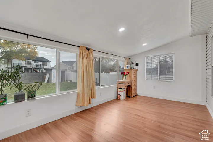 Wood-finish flooring, white walls, and a vaulted ceiling with recessed lighting