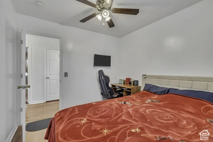 White interior walls, wood-finish flooring, and a ceiling fan with integrated lighting