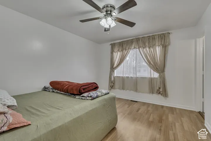 Wood-finish flooring, ceiling fan with integrated lighting, and a window with natural light