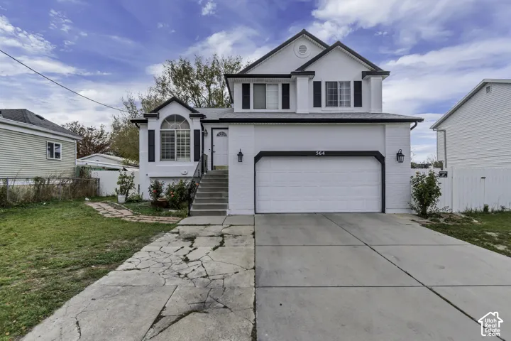 White exterior with contrasting black trim, attached two-car garage, front entry staircase, arched window detail, and exterior wall lanterns