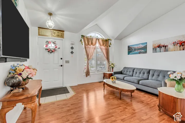 Vaulted ceilings, wood-finish flooring, and arched window with plantation shutters