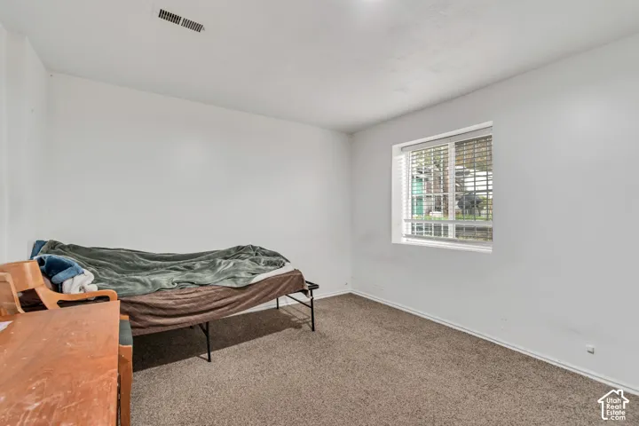 Carpeted flooring with a single window featuring blinds