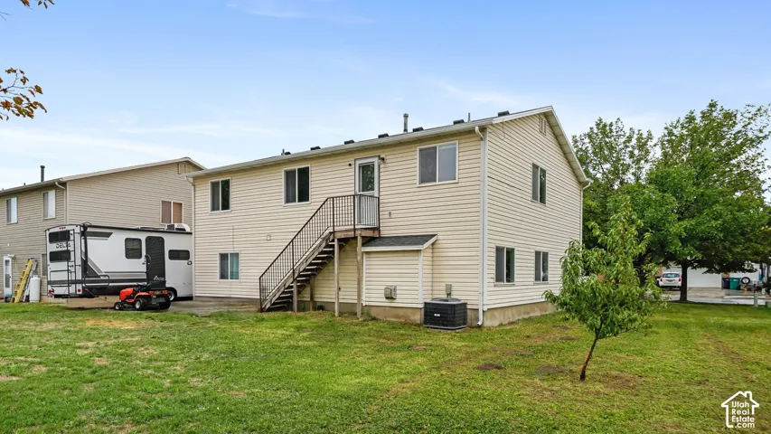 Expansive grassy yard with mature trees and a paved patio area