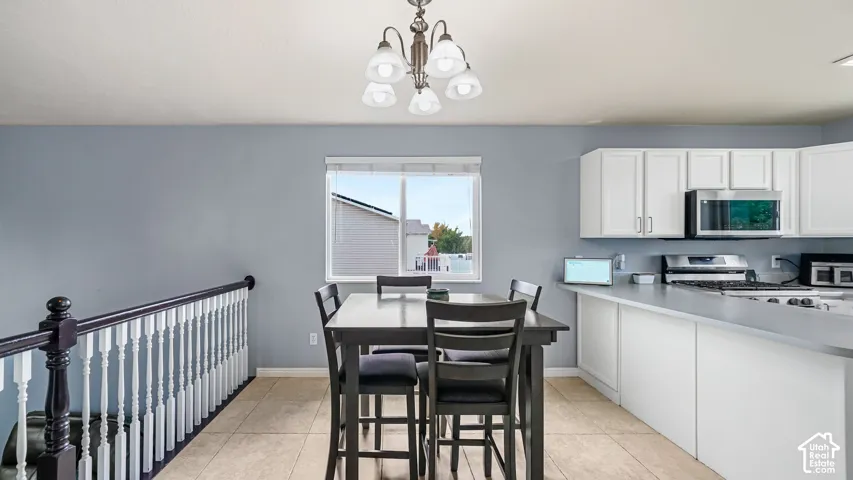 Kitchen featuring white cabinetry, stainless steel appliances, a bar-height counter, and tiled flooring