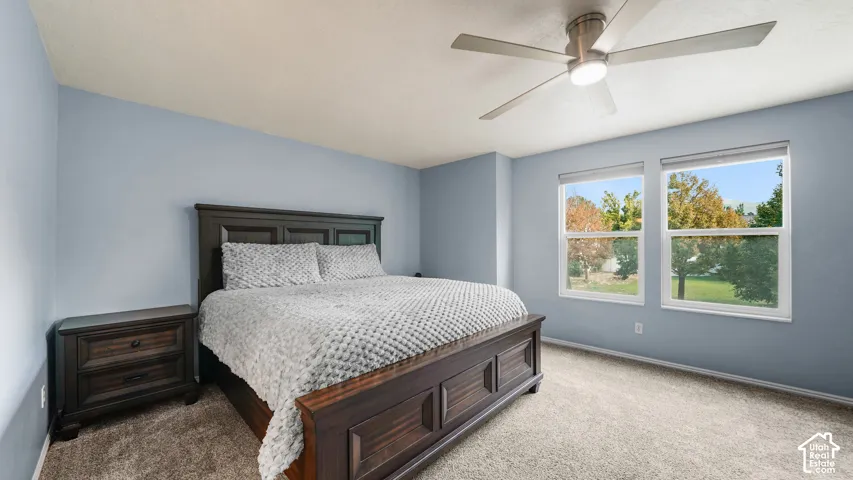 Two windows with outdoor scenery, ceiling fan with integrated lighting, wall-to-wall carpeting