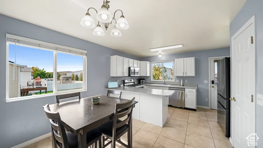 Kitchen featuring white cabinetry, stainless steel appliances, a kitchen island, and tiled flooring