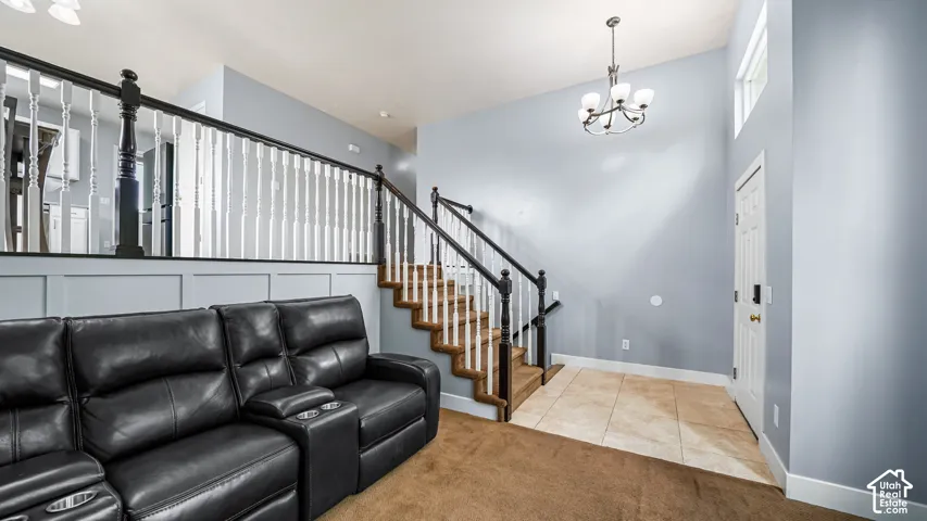 Two-story entry with a chandelier, tile flooring, and staircase with wood-finish treads and white risers