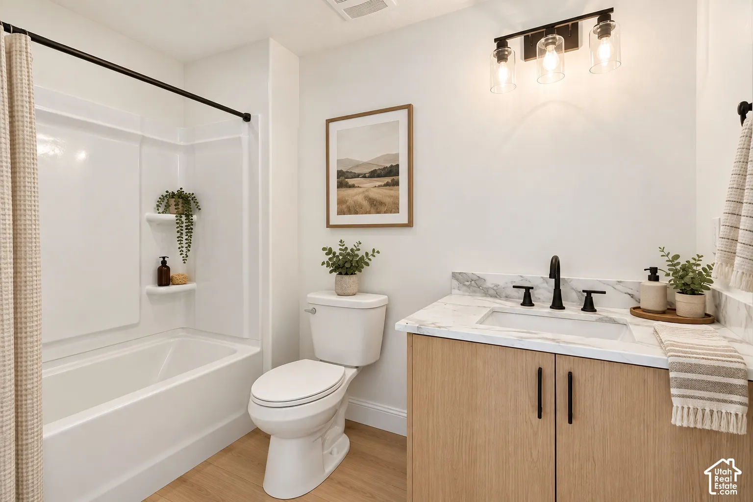 Tub/shower combination with integrated shelving, a toilet, a vanity with a rectangular undermount sink, a stone-finish countertop, and wood-finish cabinetry- VIRTUALLY STAGED