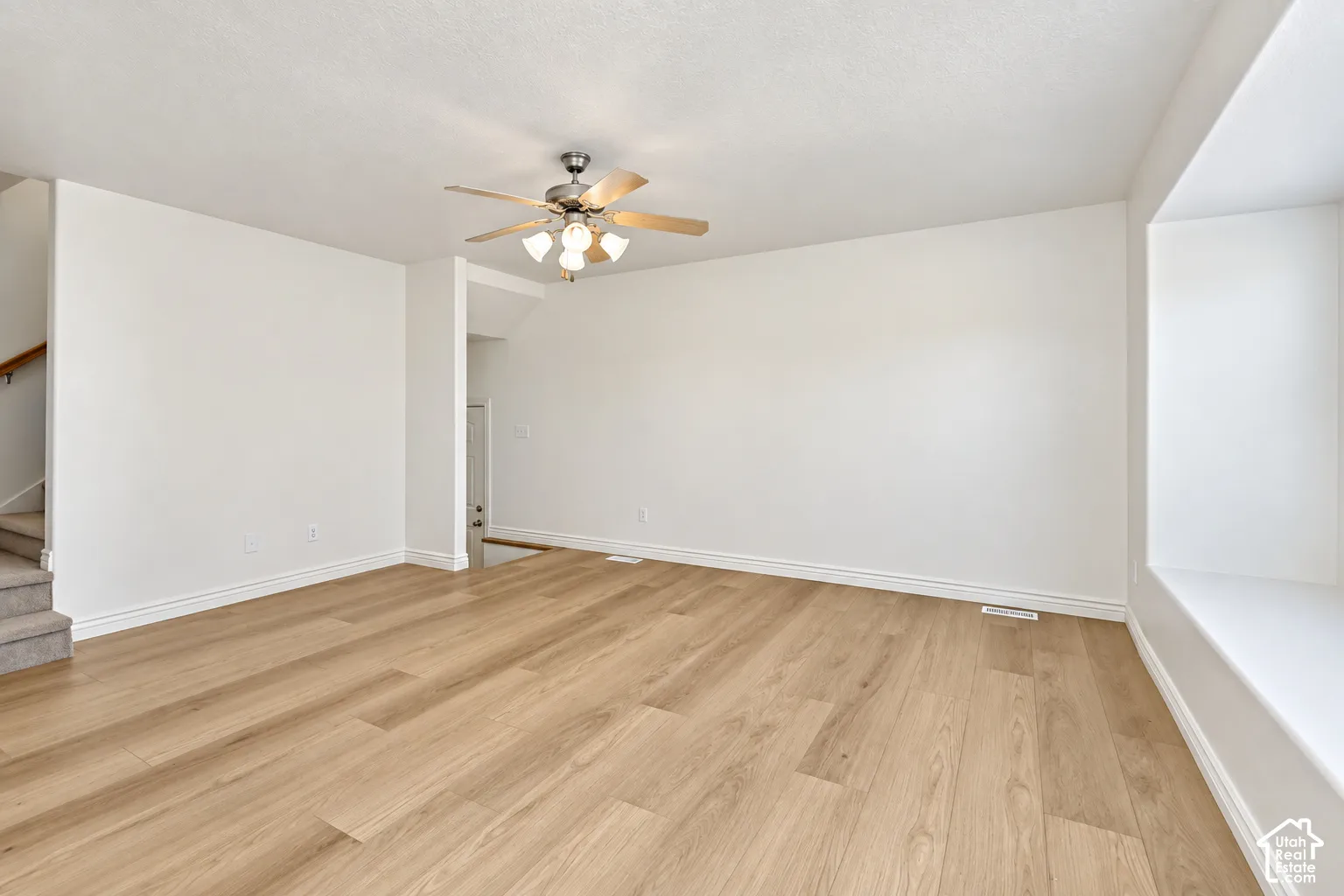Wood-finish flooring, ceiling fan with integrated lighting, window seat with a sills, white baseboards, and neutral wall tones
